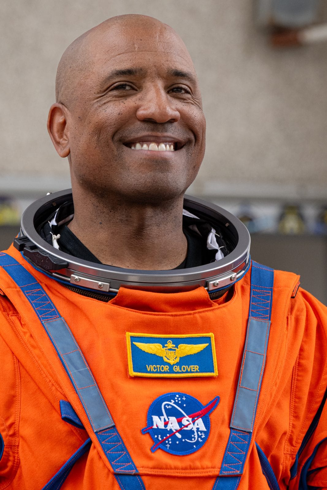 Artemis II pilot Victor Glover in his orange launch and entry suit, helmet ring open, during crew walkout at Kennedy Space Center on April 1, 2026.