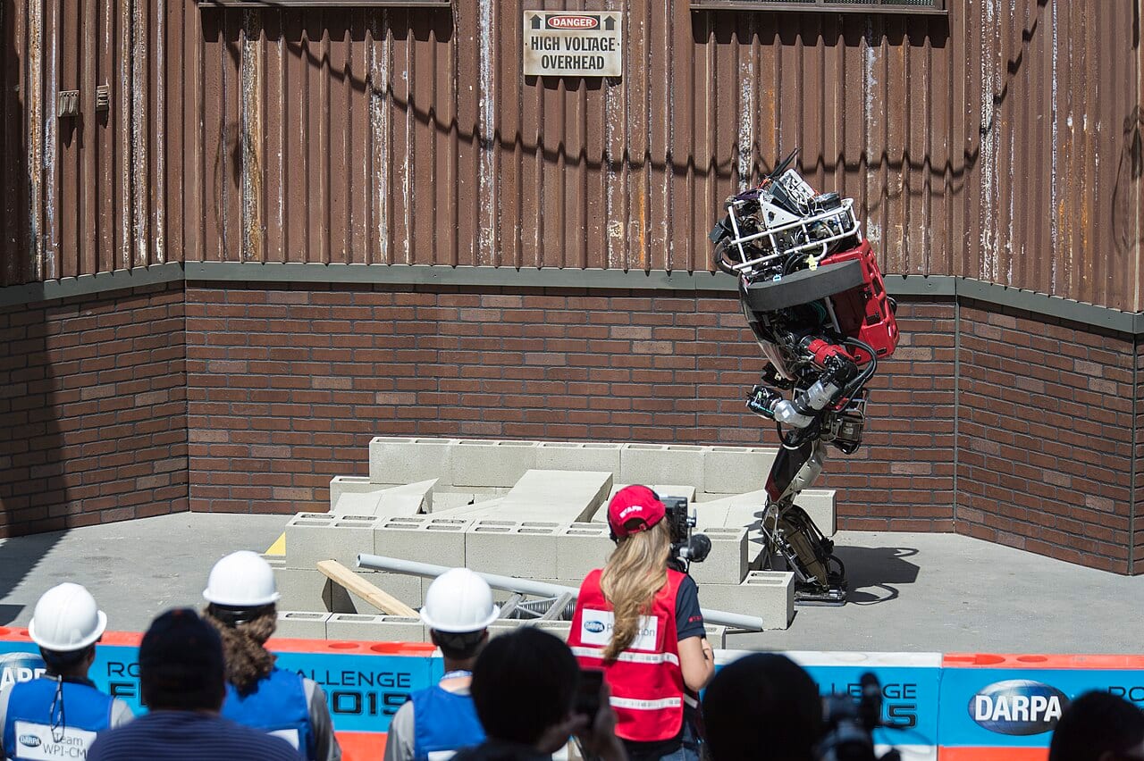 The humanoid robot WARNER navigating a debris field during the DARPA Robotics Challenge, testing whether it can complete a task outside a controlled demo setting.