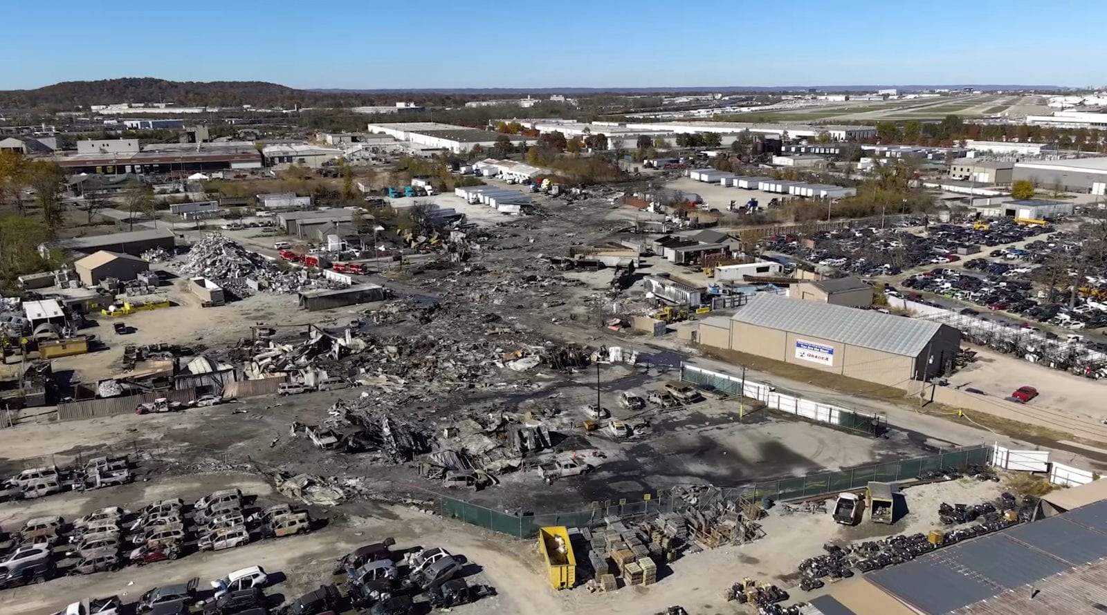 Aerial view of the burned wreckage and scorched ground at the UPS Flight 2976 crash site, amid an industrial salvage yard near Louisville Muhammad Ali International Airport.